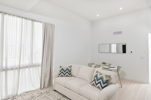 A modern living room with a sofa, a small round table, and a mirror on the wall. - South Beach Apt with Rooftop Pool & Bay Views #304 (Miami Beach)