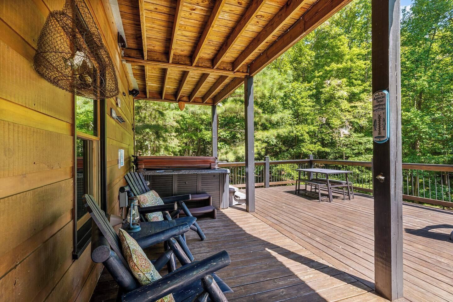 A wooden deck with outdoor seating, a hot tub, and a sign indicating trout fishing.