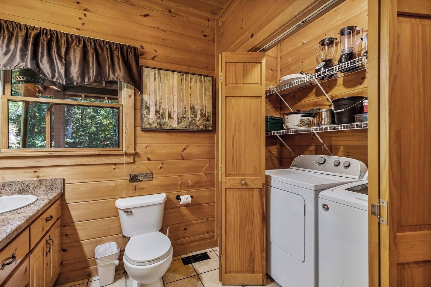 A compact wooden cabin bathroom with a toilet, sink, and washing machine.