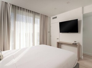 A hotel room with a bed, a TV mounted on the wall, a bedside table, and a window with curtains. - South Beach Apt: Rooftop Pool/Prime Location #201 (Miami Beach)