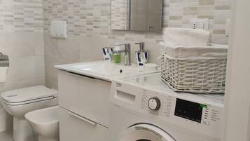 Ein modernes Badezimmer mit Waschmaschine, Toilette und Waschbecken.