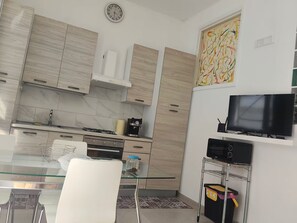 Eine moderne Küche mit einem Glastisch, Edelstahlgeräten und einem Flachbildfernseher.