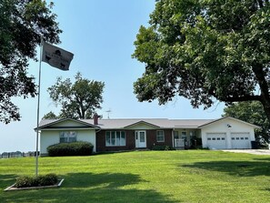 A two-story house with a garage, a front lawn, and a flag indicating it is a historic site. - Farmhouse in New Sharon (New Sharon)