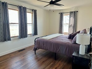 A bedroom with a bed, a ceiling fan, and a nightstand with a lamp. - Farmhouse in New Sharon (New Sharon)