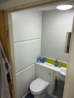 A small, compact bathroom with a white toilet, a sink, and a mirror above it. There are toiletries on the sink counter. - Apartment - Sleeps 1 - On Street Parking - Tv (Nottingham)