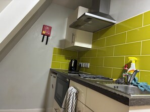 A kitchen with a microwave, toaster, and a sink with cleaning supplies. - Apartment - Sleeps 1 - On Street Parking - Tv (Nottingham)