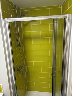 Cabina de ducha con puerta de vidrio y rociador.