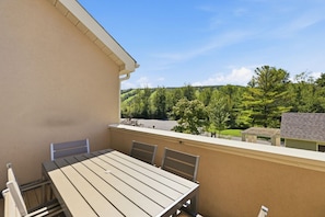 A balcony with a table and chairs, overlooking a parking area and greenery. - Renovated Alpine Retreat | Ski & Golf Views (The Blue Mountains)