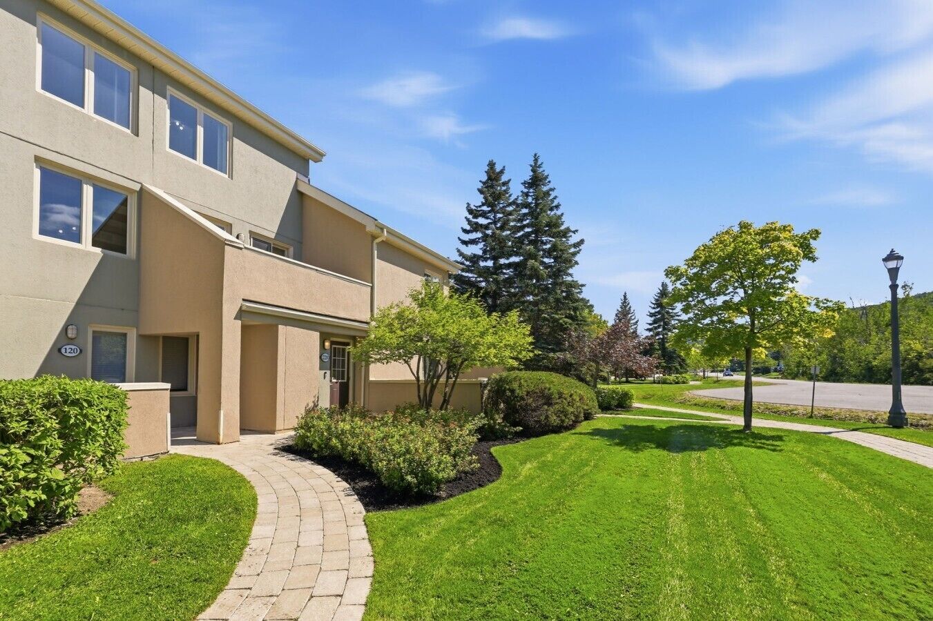 A multi-story residential building with a paved driveway and well-maintained lawn.
