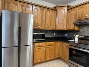 A kitchen with wooden cabinets, stainless steel appliances, and a black tiled backsplash. - Superb 4-bedroom house with AC  and large deck in charming Oxford,ohio (Oxford)