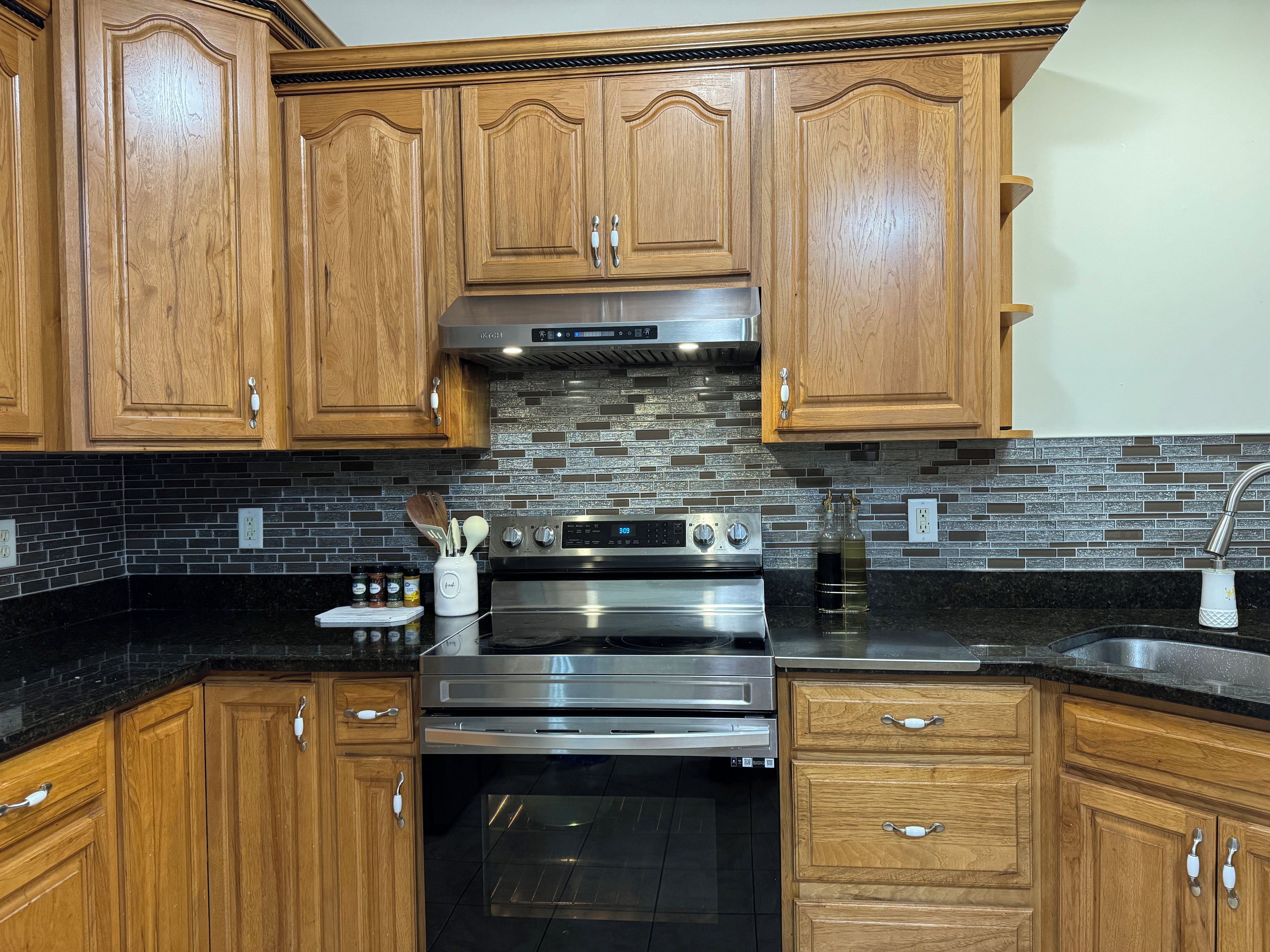 A kitchen with wooden cabinets, a stainless steel stove, and a black countertop.