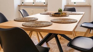 A dining area with a wooden table, black chairs, woven placemats, and a potted plant. - Gera Apartment Blue Foosball Table 7 Guests (Gera)