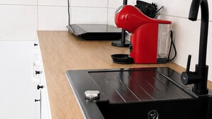 A modern kitchen with a black sink, wooden countertop, white cabinets, and a red kettle. - Gera Apartment Blue Foosball Table 7 Guests (Gera)