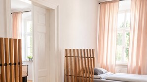 A bedroom with a bed, a sofa, a wooden partition, and a window with curtains. - Gera Apartment Blue Foosball Table 7 Guests (Gera)