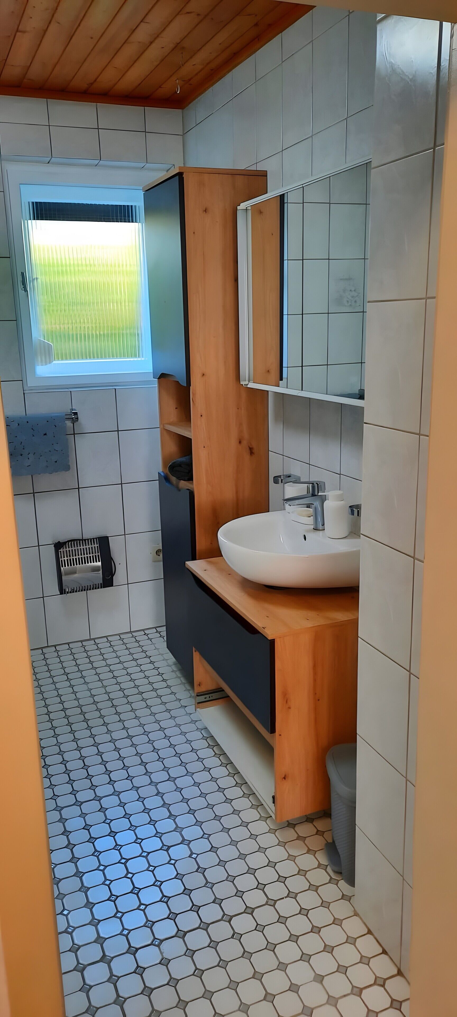 Une salle de bain moderne avec un meuble-lavabo en bois, un lavabo blanc et un grand miroir.