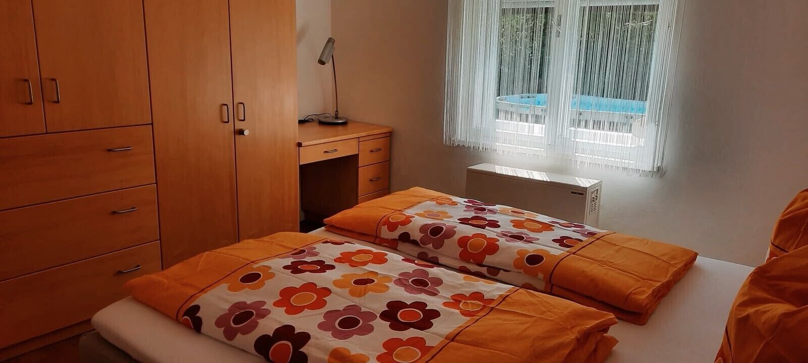 Ein Schlafzimmer mit einem Bett, einem Schreibtisch und einem fenster mit Vorhängen.