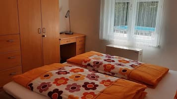Ein Schlafzimmer mit einem Bett, einem Schreibtisch und einem fenster mit Vorhängen.