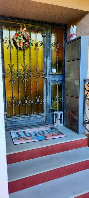 A door with a decorative wreath, a metal gate, and a welcome mat.