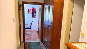 A hallway with a patterned carpet, wooden cabinets, and a door leading to another room.