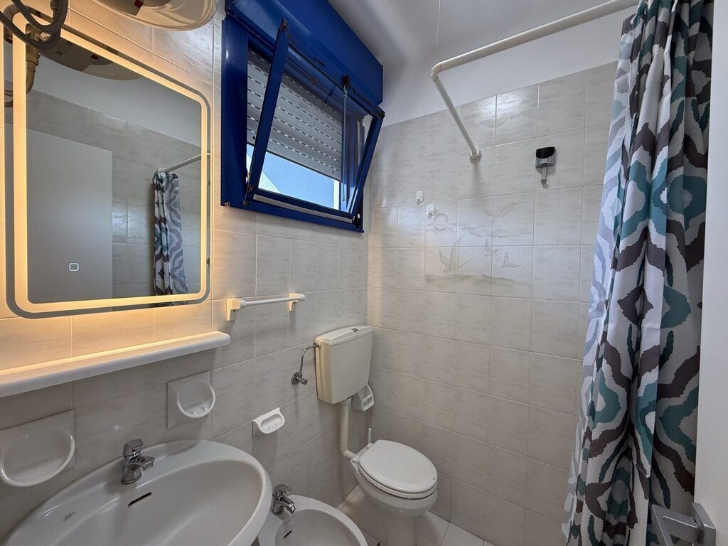 A bathroom with a white sink, a toilet, and a shower area.