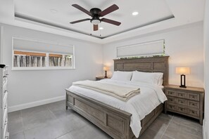A bedroom with a bed, nightstands, a ceiling fan, and a window with blinds. - Coveside Hideaway 6 - Coastal Haven (Deerfield Beach)