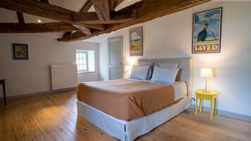 Une chambre avec un plafond en bois, un lit recouvert d’une couverture marron, une lampe de chevet et une affiche accrochée au mur.