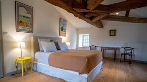 Um quarto com cama, uma mesinha, uma cadeira e um abajur.