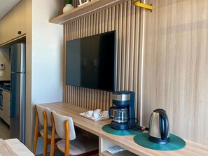 A modern kitchen with a built-in TV, a coffee maker, and a kettle on the counter. - Waimea Beach por YOLO (Ipojuca)