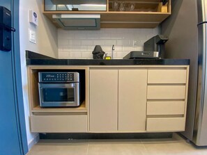 Une cuisine moderne équipée d’un four à micro-ondes encastré, d’une machine à café et d’un réfrigérateur en acier inoxydable.