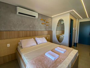 Une chambre d’hôtel équipée d’un lit, d’un appareil de climatisation, d’un miroir fixé au mur et d’une porte.