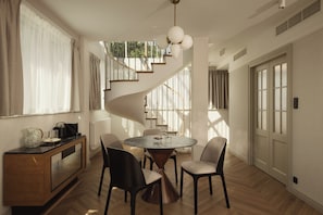 Un interior modern amb una escala espirala, una taula rodona i cadires.