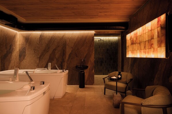 A modern bathroom with a large bathtub, a sink, and a chair.