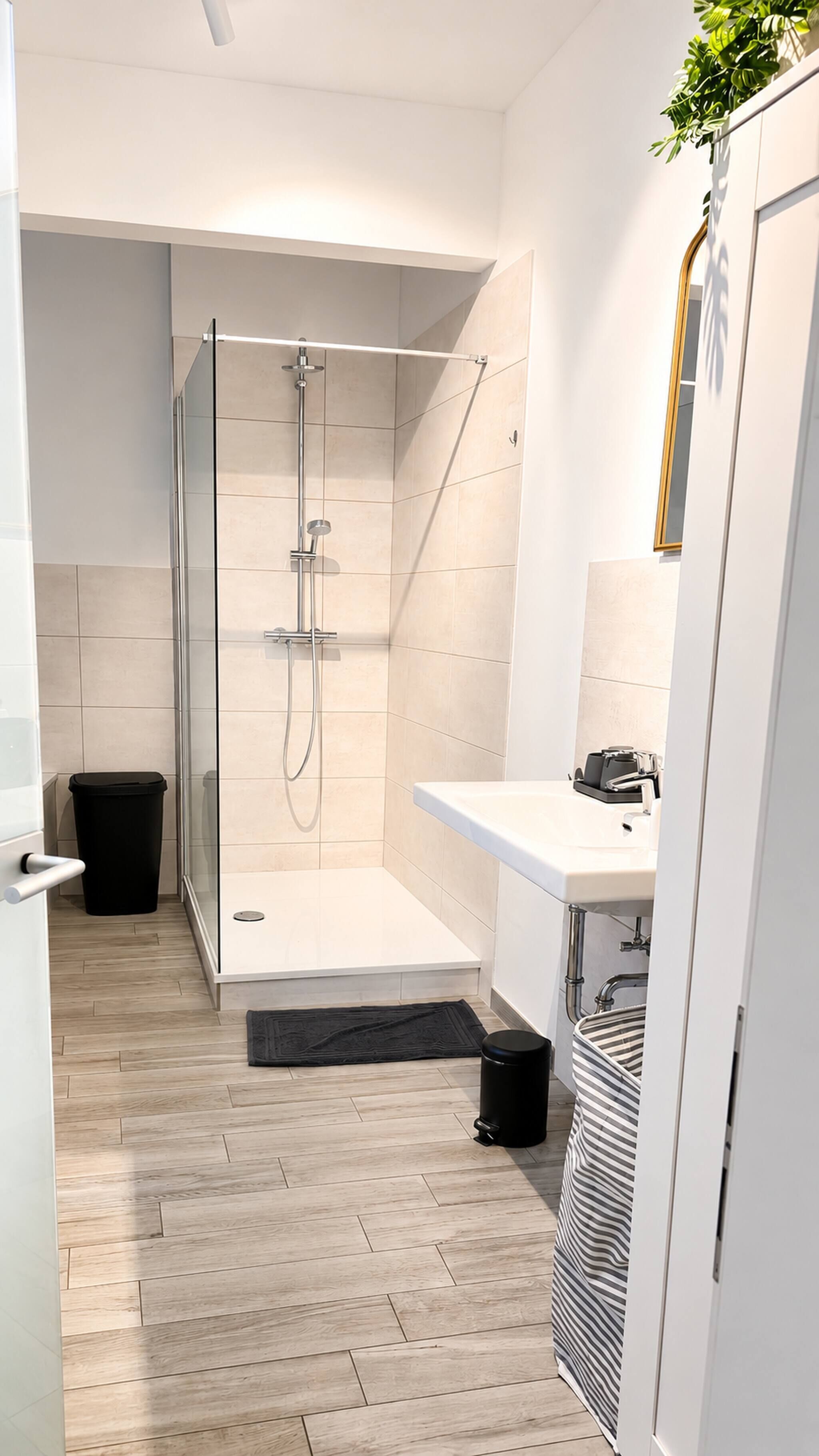 A modern bathroom with a glass-enclosed shower, a white sink, and a mirror.