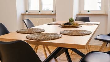 Ein Essbereich mit einem Holztisch, schwarzen Stühlen, gewebten Platzsets und einem Blumentopf.