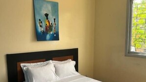 Een slaapkamer met een bed, een nachtkastje, een raam met uitzicht en een schilderij aan de muur.