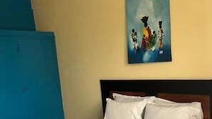 Een kamer met een bed, een blauwe garderobe en een schilderij aan de muur.