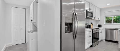 A modern kitchen with stainless steel appliances, white cabinetry, and a window providing natural light.