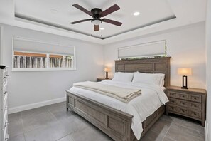 A bedroom with a bed, nightstands, a ceiling fan, and a window with blinds. - Coveside Hideaway 4 - Coastal Oasis (Deerfield Beach)
