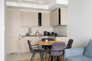 A compact kitchen with a dining area, including a table, chairs, and a coffee machine. - Porto Mare Seaside with Parking and Gym (Gdańsk)
