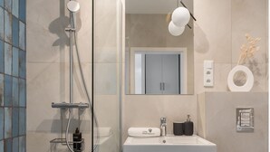 A modern bathroom with a glass shower enclosure, a sink with a mirror above, and a toilet.