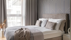 A bedroom with a bed, pillows, a bedside table, and a wall with geometric patterns.