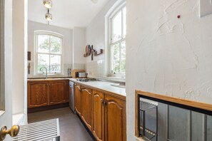 A kitchen with wooden cabinets, a stainless steel sink, and a built-in stove. - GuestReady - Charming Fulham Retreat with Balcony (London)