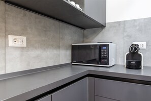 A modern kitchen with a microwave, a coffee maker, and a power outlet on the countertop. - Sporting by Wonderful Italy (Sirmione)