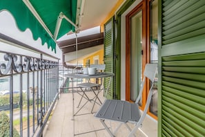 A balcony with a table and chairs, a green awning, and a view of the sea. - Sporting by Wonderful Italy (Sirmione)