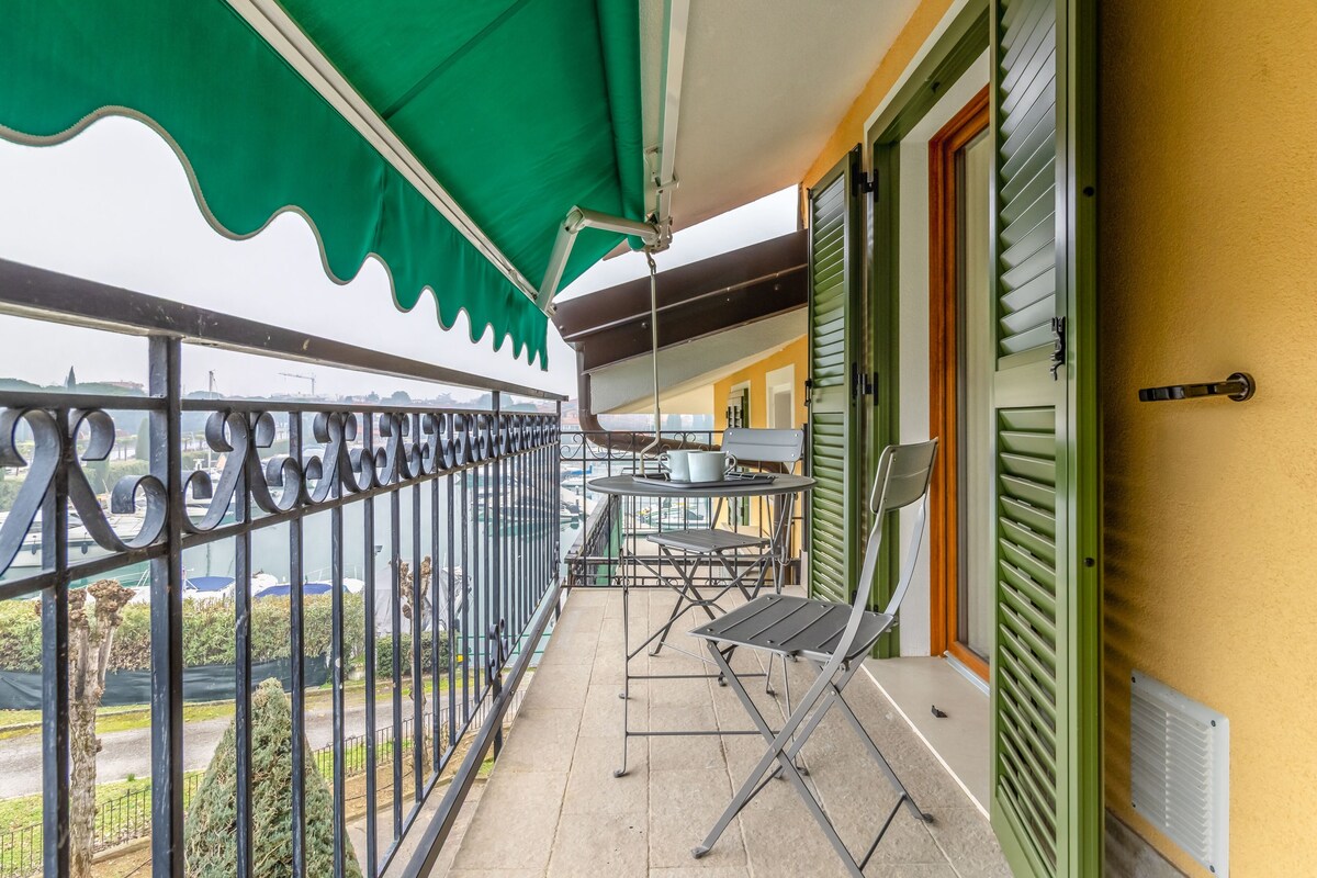 A balcony with a green awning, a table with chairs, and a view of the cityscape.