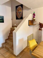 A staircase with a wooden finish, a painting on the wall, and a statue on the landing.