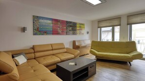 A living room with a tan sectional sofa, a yellow sofa, a coffee table, and a piano. - Holiday Home - Cityhouse WG9 - 6 Guests - 3BR (Marktheidenfeld)