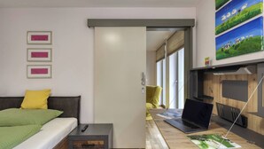 A modern bedroom with a bed, bedside table, and a desk with a laptop. - Holiday Home - Cityhouse WG9 - 6 Guests - 3BR (Marktheidenfeld)