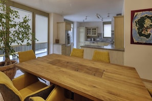 A modern kitchen with white cabinets, a central island, and a dining area with a wooden table and yellow chairs. - Holiday Home - Cityhouse WG9 - 6 Guests - 3BR (Marktheidenfeld)