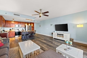 A modern living room with a flat-screen TV, white furniture, and a dining area with chairs and a table. - 🏖️Laketown Wharf 316~Walk to Beach~5 Pools~ Putting Green~ Fitness Center🏖️ (Panama City)